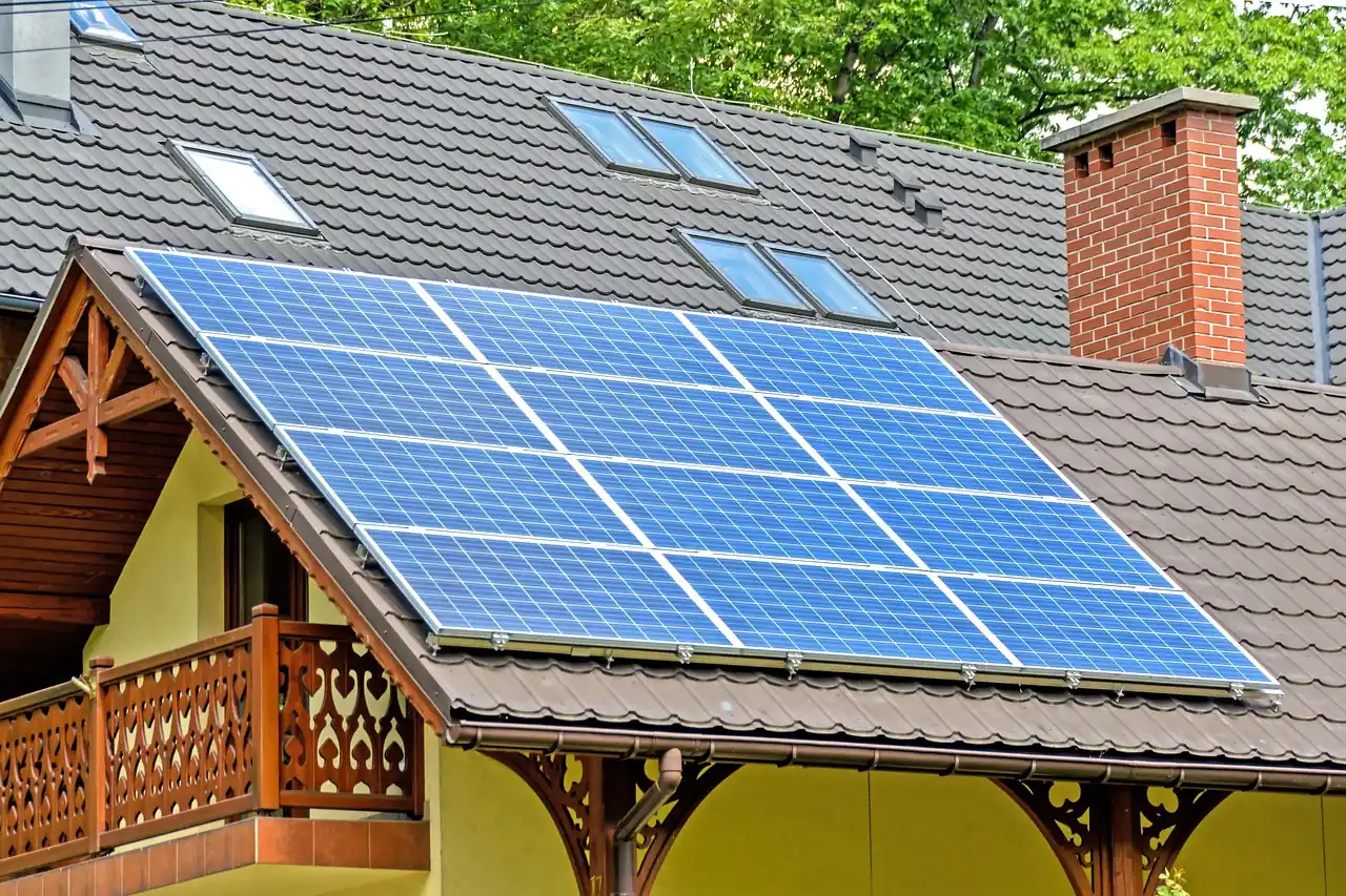 Maison au toit couvert de panneaux solaires, entourée d'arbres