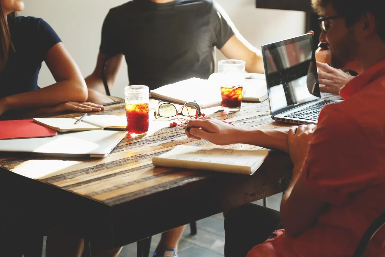Personnes travaillant autour d'une table avec des carnets et un ordinateur